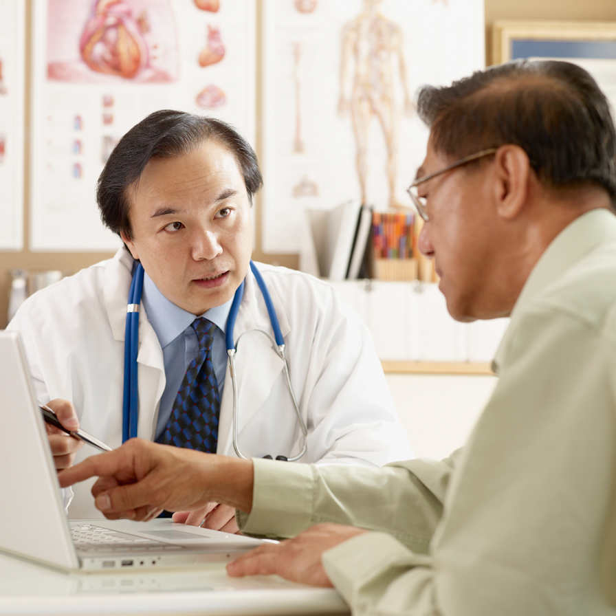 Male patient pointing to computer screen while in discussion with a male doctor